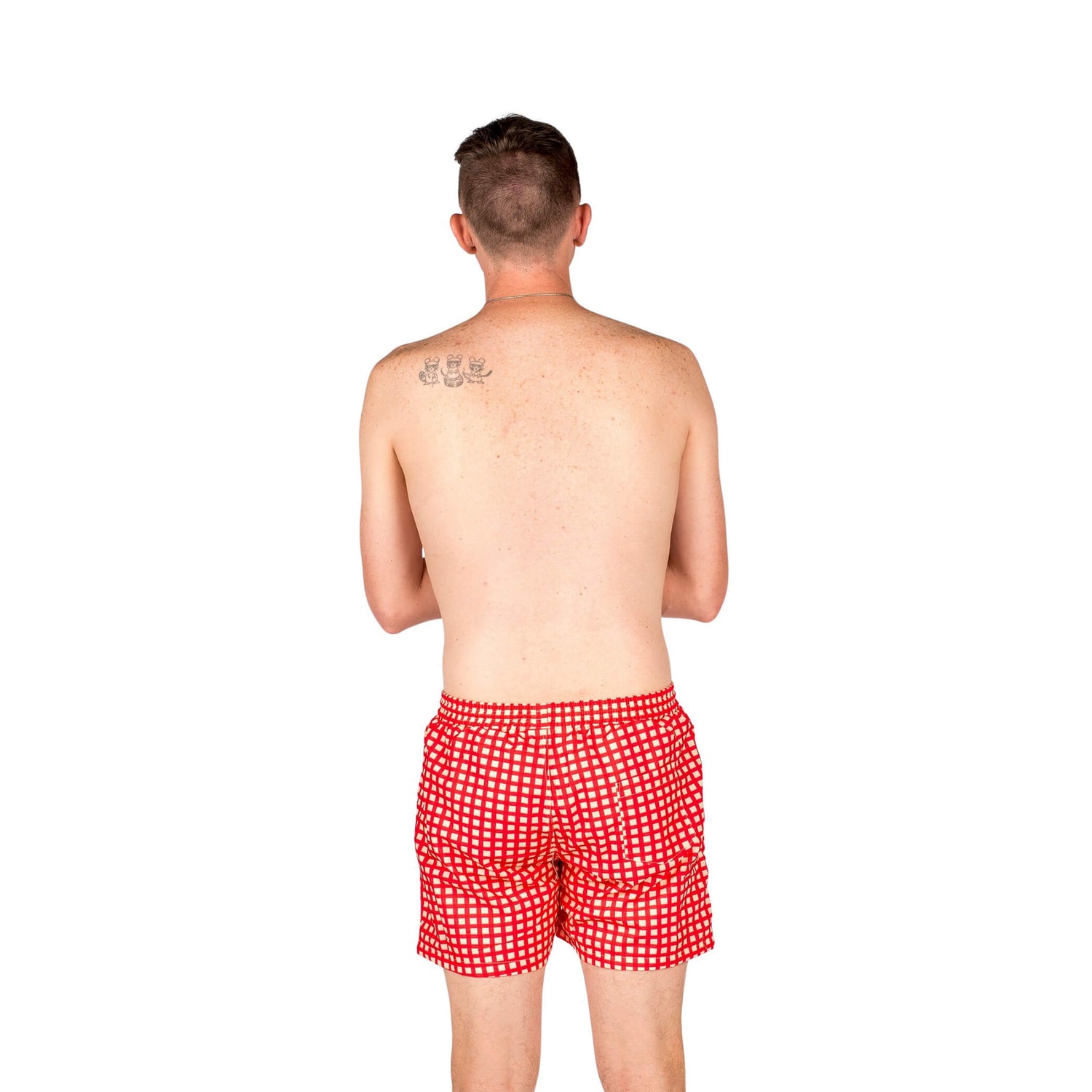Male model facing away from the camera. He is shirtless and wearing Vibrant Hounds Red Gingham swim shorts.,