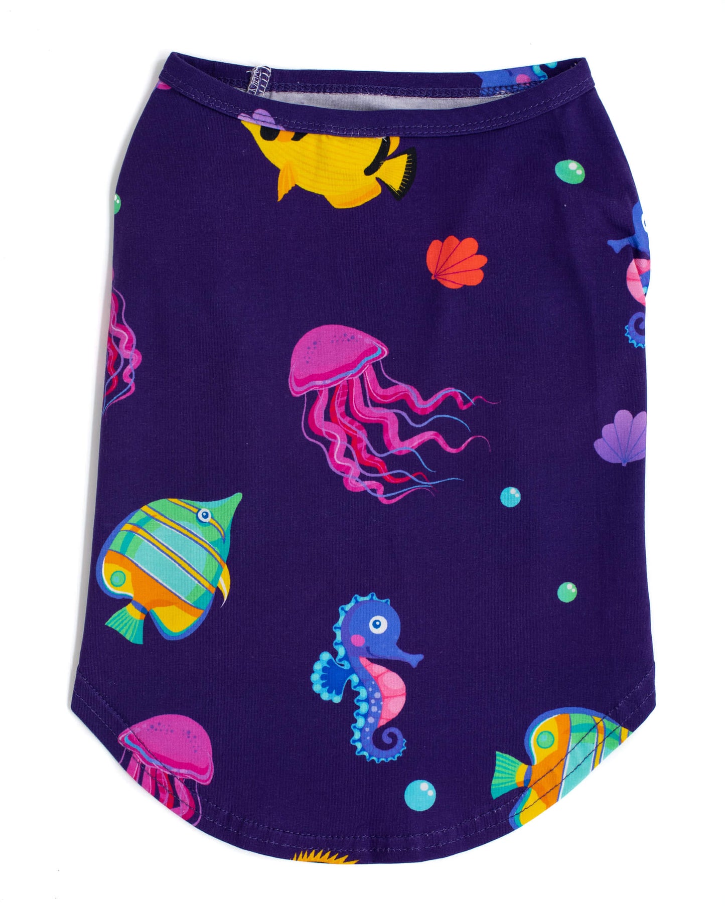 Vibrant Hound's "Magic Sea" shirt for dogs. A purple shirt with vibrant tropical fish printed on it, laid flat on a surface.