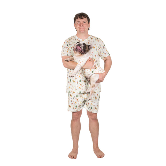 Man wearing Santa’s Workshop matching Christmas pyjamas holding a French Bulldog in the matching Christmas dog shirt.